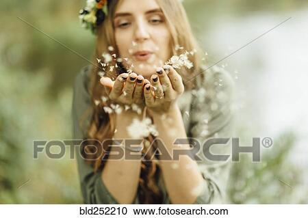 Stock Image - Middle Eastern woman blowing dandelion seeds. Fotosearch