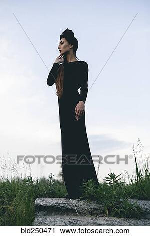 Stock Image - Middle Eastern woman wearing black dress standing on stone. Fotosearch