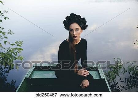 Stock Photo - Middle Eastern woman wearing black dress in boat on lake. Fotosearch