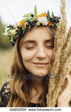 Middle Eastern woman wearing flower crown holding wheat to face View Large Photo Image Picture - Middle Eastern woman wearing flower crown holding wheat to face. Fotosearch
