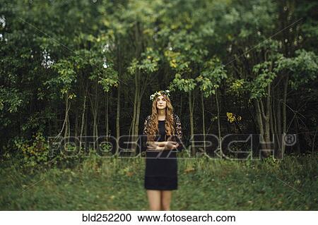 Stock Image - Middle Eastern woman wearing flower crown in woods. Fotosearch