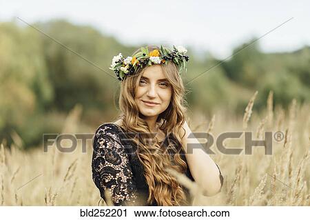 Stock Image - Middle Eastern woman wearing flower crown in field. Fotosearch