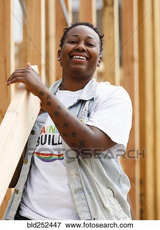Stock Photo - Mix race volunteer carrying lumber at construction site. Fotosearch