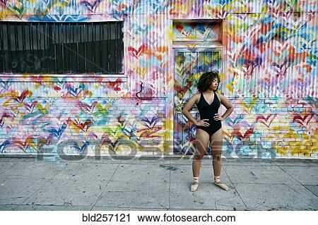Stock Image - Mixed race ballet dancer resting on sidewalk. Fotosearch