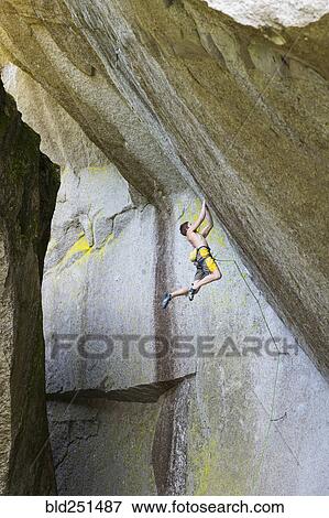 Stock Photo - Mixed race boy hanging from rock. Fotosearch