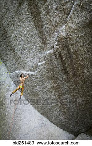 Stock Photo - Mixed race boy hanging from rock. Fotosearch