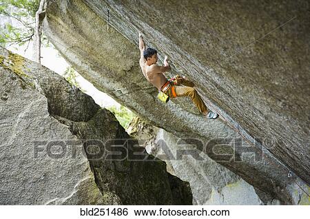 Stock Photograph - Mixed race boy rock climbing. Fotosearch