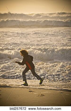 Stock Image - Mixed race boy running on beach. Fotosearch