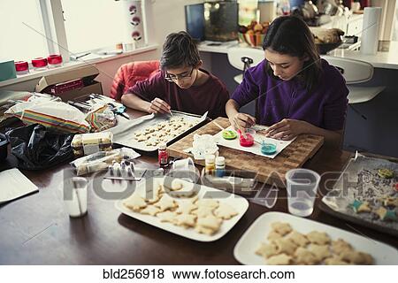 Stock Photo - Mixed race brother and sister decorating cookies. Fotosearch