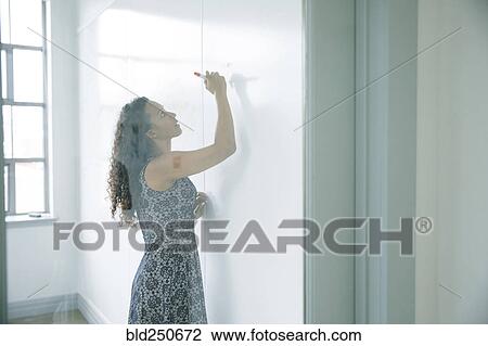 Stock Image - Mixed race businesswoman writing on whiteboard. Fotosearch