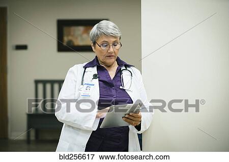 Stock Photo - Mixed race doctor using digital tablet. Fotosearch