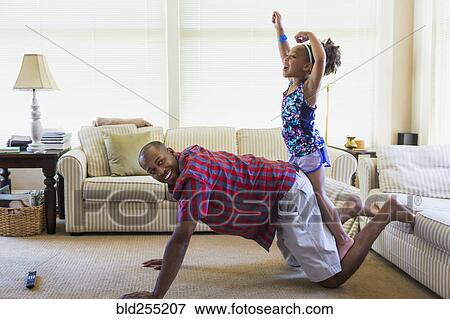 Stock Photo - Mixed race father and daughter playing on floor in livingroom. Fotosearch