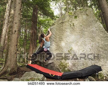 Stock Image - Mixed race girl climbing rock. Fotosearch