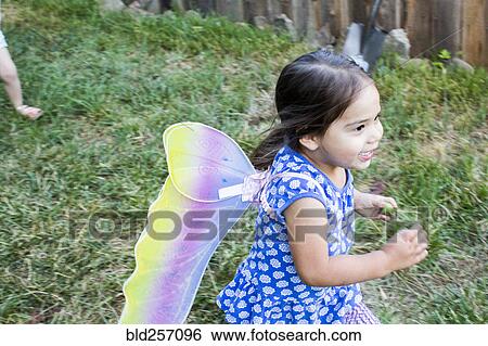 Stock Photograph - Mixed race girl running wearing fairy wings. Fotosearch