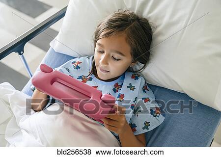 Stock Photo - Mixed race girl using digital tablet in hospital bed. Fotosearch