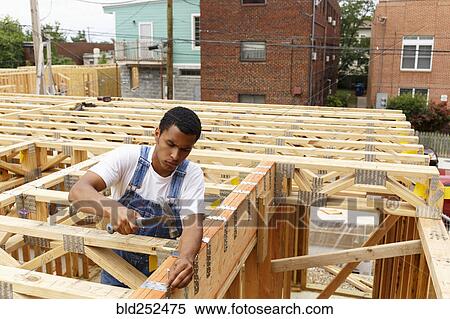 Mixed race man hammering nail at construction site View Large Photo Image Stock Photography - Mixed race man hammering nail at construction site. Fotosearch