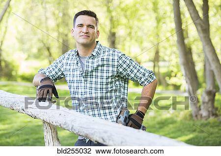 Mixed race man holding drill cleaning on the wooden fence View Large Photo Image Stock Image - Mixed race man holding drill cleaning on the wooden fence. Fotosearch