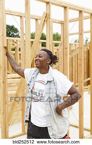 Stock Image - Mixed race man leaning on lumber at construction site. Fotosearch