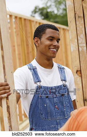 Stock Image - Mixed race man smiling at construction site. Fotosearch