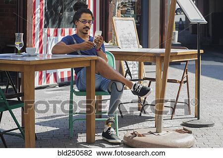 Mixed race man with prosthetic leg texting on cell phone at sidewalk cafe View Large Photo Image Stock Image - Mixed race man with prosthetic leg texting on cell phone at sidewalk cafe. Fotosearch