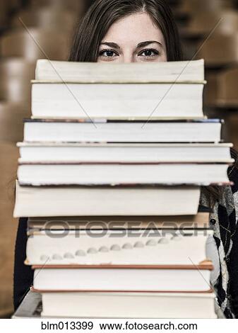 Stock Photo - Mixed race student holding stack of books. Fotosearch