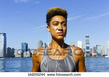 Mixed race woman at waterfront listening to earbuds View Large Photo Image Picture - Mixed race woman at waterfront listening to earbuds. Fotosearch
