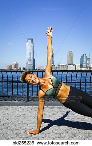 Stock Photograph - Mixed race woman balancing on arm at waterfront. Fotosearch