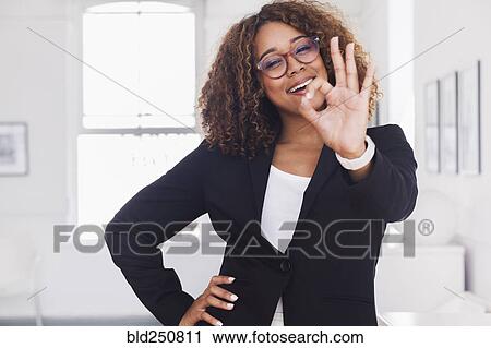 Stock Image - Mixed race woman gesturing okay in gallery. Fotosearch