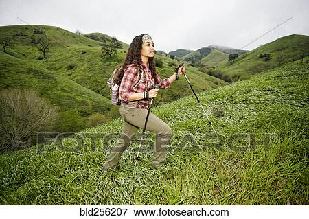 Stock Photo - Mixed race woman hiking with walking sticks. Fotosearch