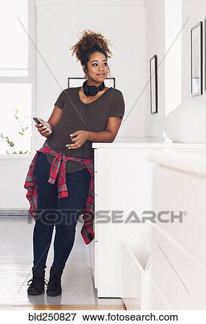 Stock Photo - Mixed race woman holding cell phone. Fotosearch