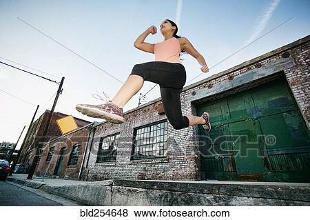 Mixed race woman jumping off loading dock View Large Photo Image Stock Photo - Mixed race woman jumping off loading dock. Fotosearch