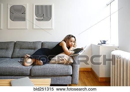 Mixed race woman laying on sofa reading book View Large Photo Image Stock Photography - Mixed race woman laying on sofa reading book. Fotosearch