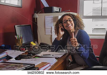 Mixed race woman listening to headphones at computer View Large Photo Image Stock Image - Mixed race woman listening to headphones at computer. Fotosearch