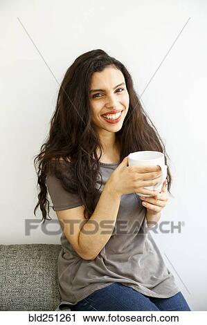 Mixed race woman on sofa drinking coffee View Large Photo Image Stock Image - Mixed race woman on sofa drinking coffee. Fotosearch