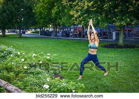 Stock Photo - Mixed race woman performing yoga in park. Fotosearch