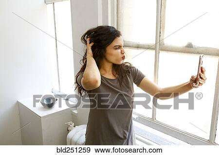 Stock Photo - Mixed race woman posing for cell phone selfie. Fotosearch