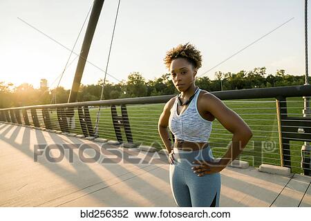 Stock Image - Mixed race woman resting on bridge. Fotosearch