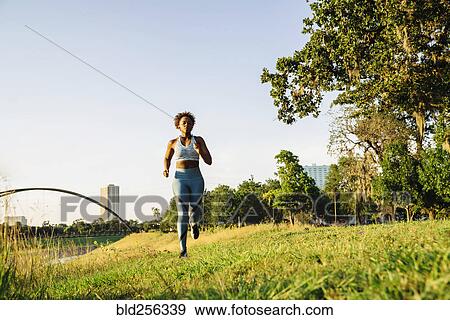 Stock Photo - Mixed Race woman running in grass near waterfront. Fotosearch