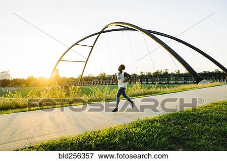 Stock Photo - Mixed race woman running on path in park. Fotosearch