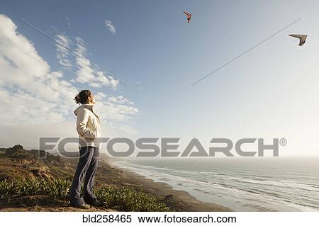 Mixed Race woman standing on beach watching gliders View Large Photo Image Stock Photography - Mixed Race woman standing on beach watching gliders. Fotosearch