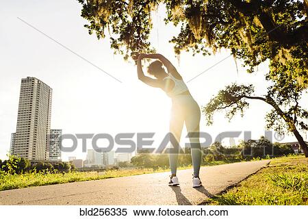 Mixed Race woman stretching on running path in park View Large Photo Image Stock Photography - Mixed Race woman stretching on running path in park. Fotosearch