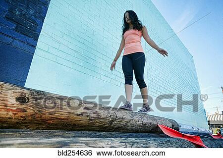 Stock Photograph - Mixed race woman walking on log. Fotosearch