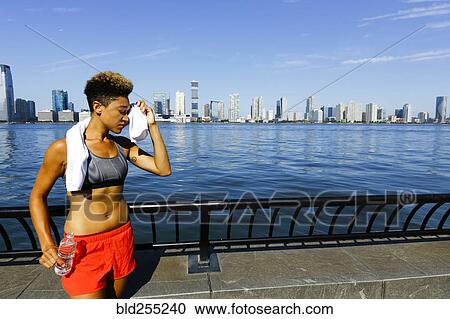 Mixed race woman wiping forehead with towel at waterfront View Large Photo Image Stock Image - Mixed race woman wiping forehead with towel at waterfront. Fotosearch