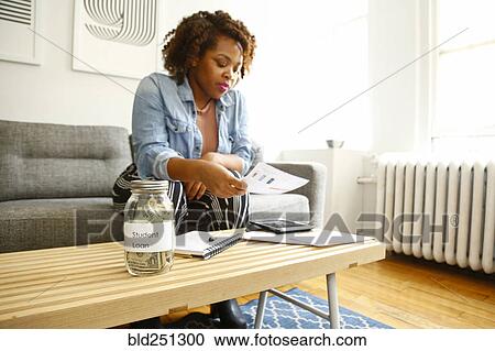 Stock Photography - Mixed race woman with student loan reading paperwork. Fotosearch - Search Stock Photos, Pictures, Wall Murals, Images, and Photo Clipart