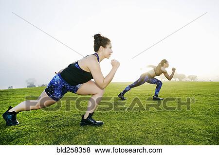 Mixed race women stretching legs in field View Large Photo Image Stock Photo - Mixed race women stretching legs in field. Fotosearch