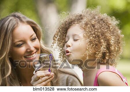 Stock Photo - Mother and daughter blowing bubbles. Fotosearch