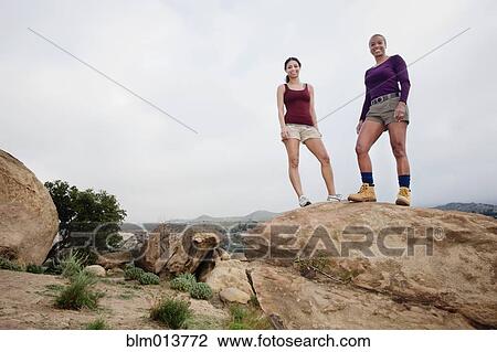 Stock Image - Mother and daughter standing on top of rock. Fotosearch