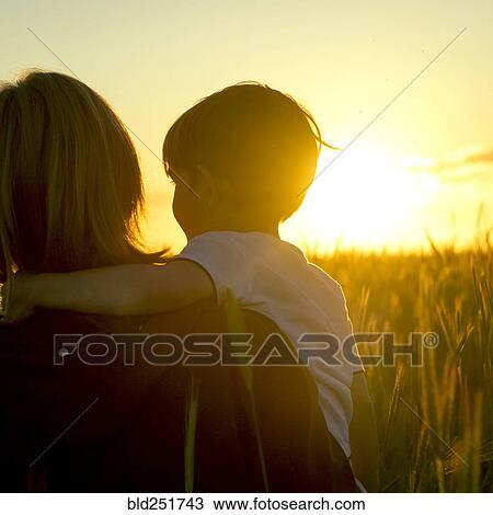 Mother carrying son in field of wheat at sunset View Large Photo Image Stock Image - Mother carrying son in field of wheat at sunset. Fotosearch