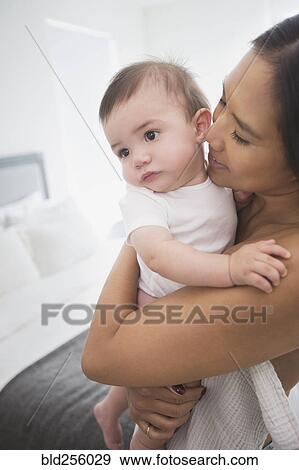 Stock Photo - Mother hugging baby son in bedroom. Fotosearch