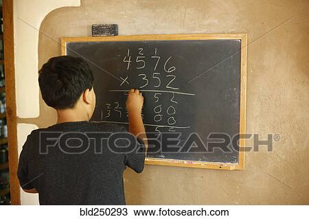 Stock Image - Native American boy solving equation on blackboard. Fotosearch